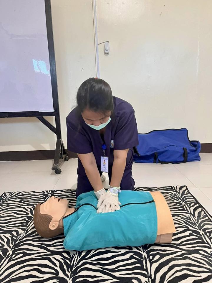 Certified Filipino caregiver performing life-saving chest compressions on an adult CPR training mannequin dummy in KL